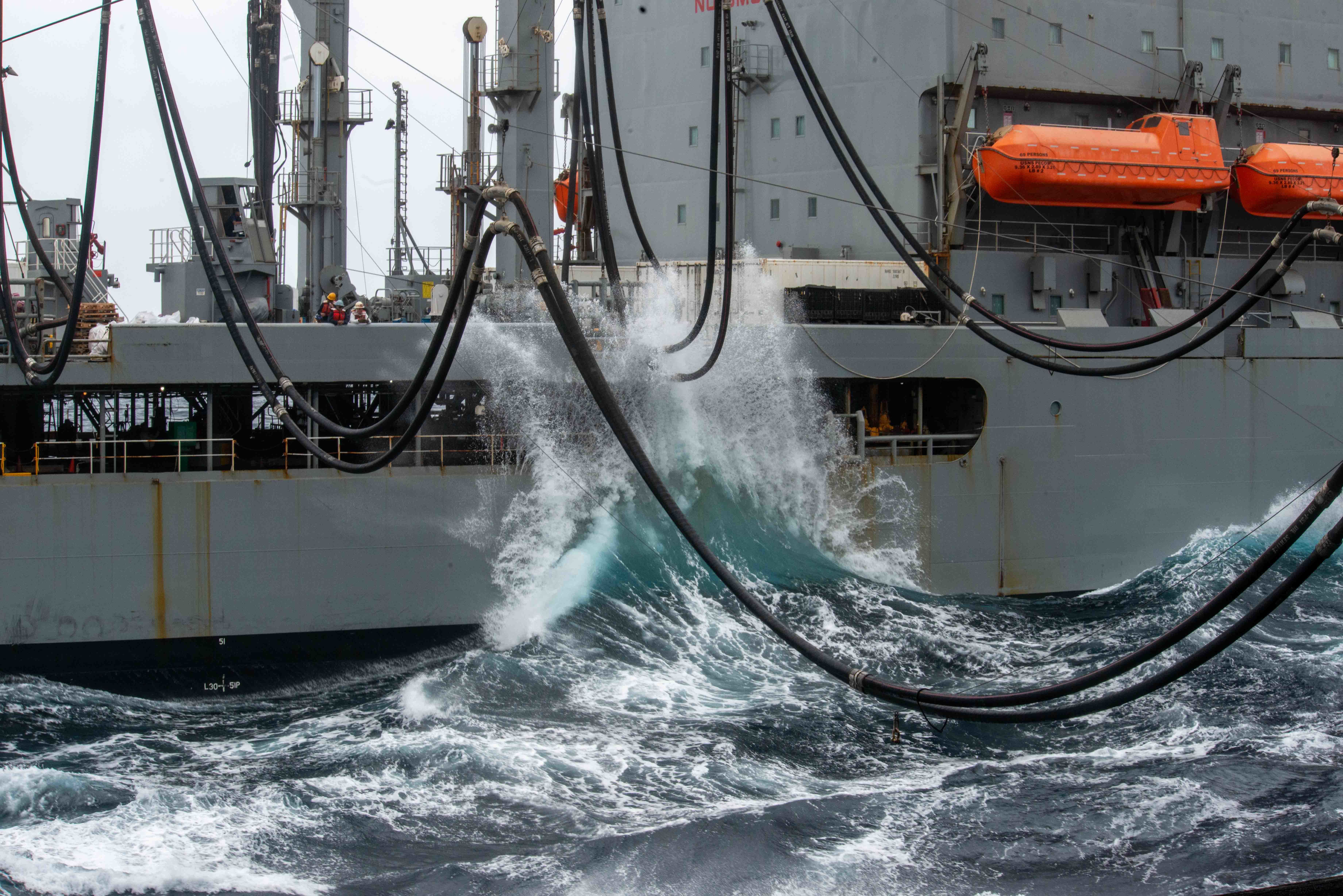 Waves crash against the Military Sealift Command fleet replenishment oiler USNS Pecos (T-AO 197) during a replenishment-at-sea with the aircraft carrier USS Ronald Reagan (CVN 76)