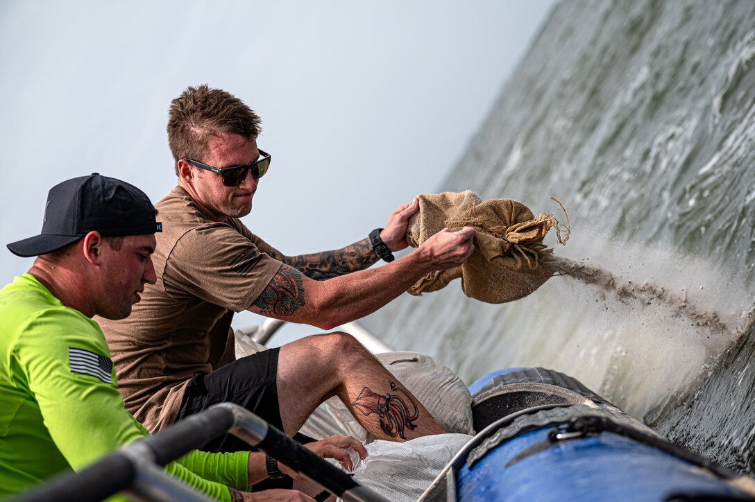Photo of Airmen dumping sand off a boat