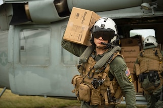 Hospital Corpsman 3rd Class Jace Borowiak carries a box of food from an MH-60S Sea Hawk helicopter during a humanitarian aid mission supporting the U.S. Agency for International Development (USAID), Aug. 25.