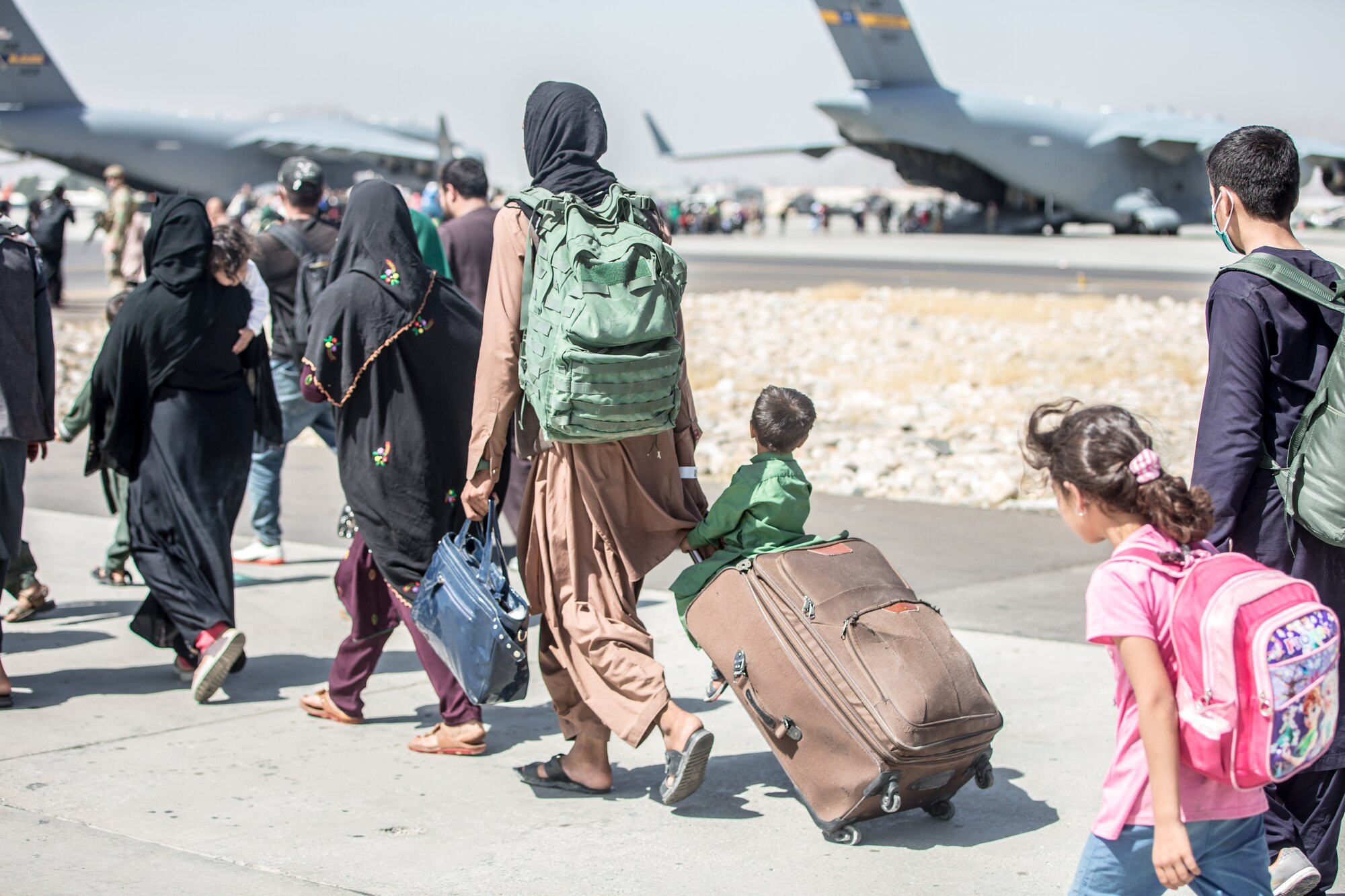 A child looks at the aircraft as he is strolled towards his flight during an evacuation at Hamid Karzai International Airport, Kabul, Afghanistan, Aug. 24. Reserve Citizen Airmen are playing a huge role in what is being described by senior U.S. government officials as one of the largest airlift operations in history. The C-17 Globemaster III aircraft were operated by crews from the 315th Airlift Wing. (U.S. Marine Corps photo by Sgt. Samuel Ruiz).