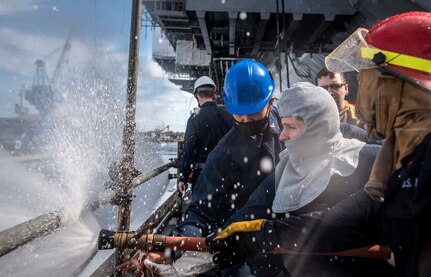 Sailors discharge a hose during a fire drill aboard the aircraft carrier USS George H. W. Bush (CVN 77).