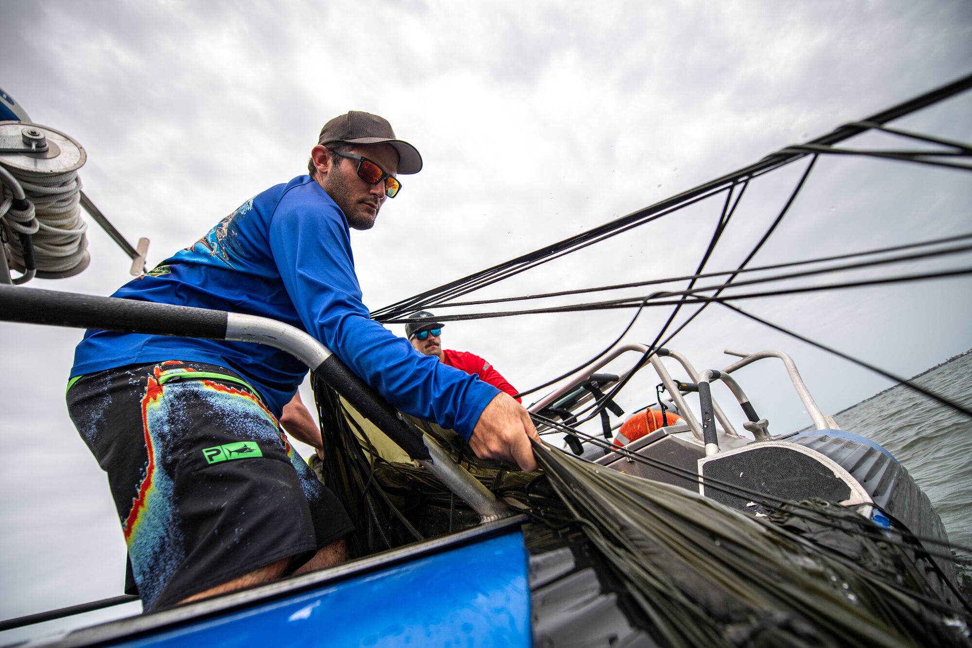 Photo of person pulling a parachute into a boat from the water