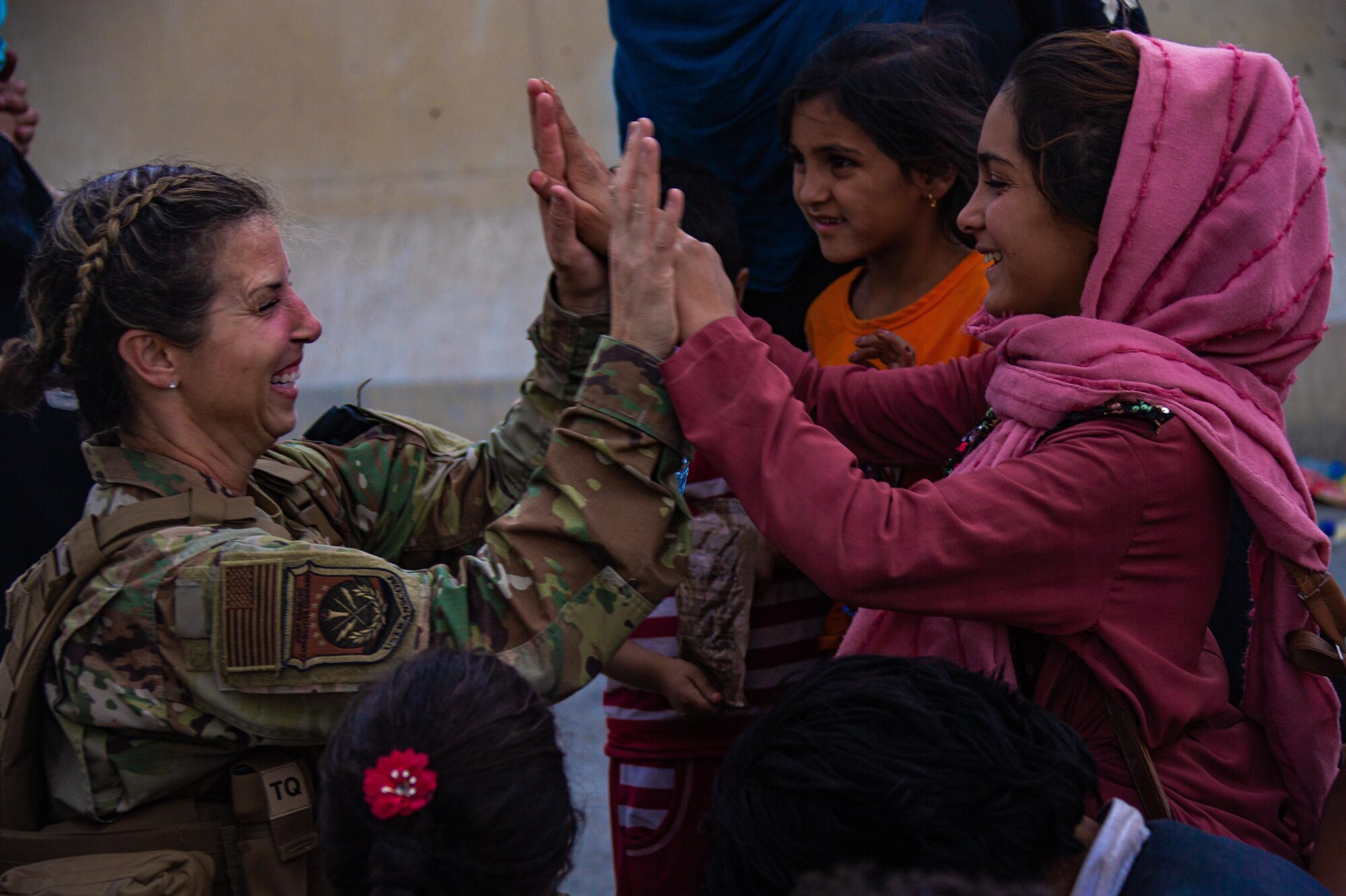 A Reserve Citizen Airmen with the Joint Task Force-Crisis Response high fives child after helping reunite their family at Hamid Karzai International Airport, Afghanistan, Aug. 20. U.S. service members are assisting the Department of State with a Non-combatant Evacuation Operation (NEO) in Afghanistan