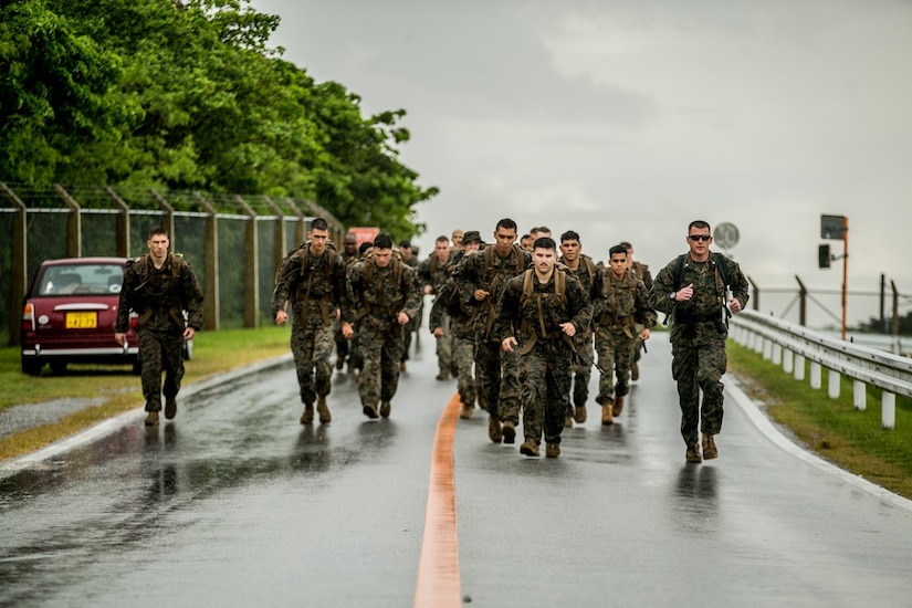 Marines run on a wet road.