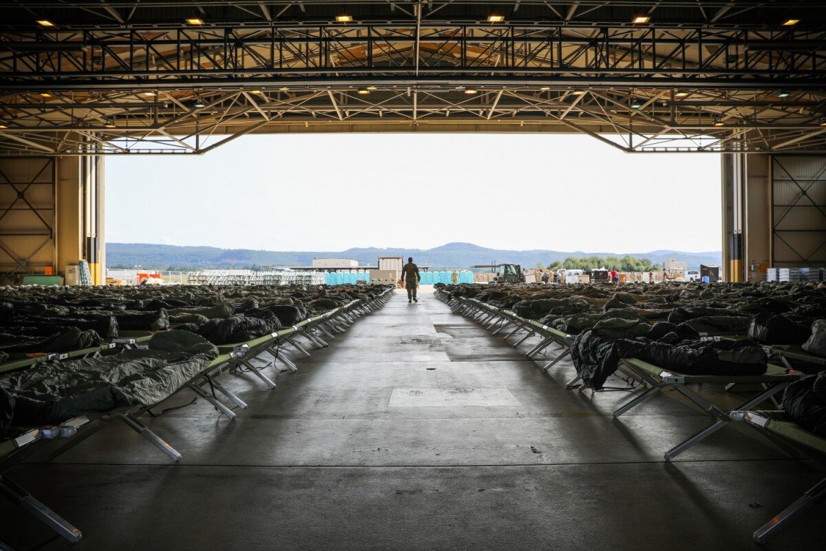 A U.S. Army Soldier from the 21st Theater Sustainment Command, Special Troops Battalion, walks through a hanger inspecting cots at Ramstein Air Base, Germany, Aug. 21, 2021. The 21st TSC supports the Department of State in the transportation, housing, and sustainment of U.S. Citizens, Special Immigrant Visa applicants, and other at-risk Afghans evacuated from Afghanistan during Operation Allies Refuge. (U.S. Army photo by Spc. Katelyn Myers)