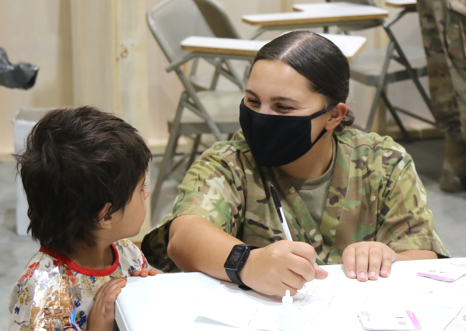 A U.S. Army National Guard Soldier assigned to Task Force Spartan, U.S. Army Central, assists an Afghan evacuee with a medical screening process as one of the first steps in his arrival at Camp Buehring, Kuwait, Aug. 25, 2021. USARCENT Soldiers from all components continue to work with their U.S. Central Command and Department of State teammates to support Afghanistan evacuation efforts with transportation, security, logistics and medical assistance at locations in Kuwait.