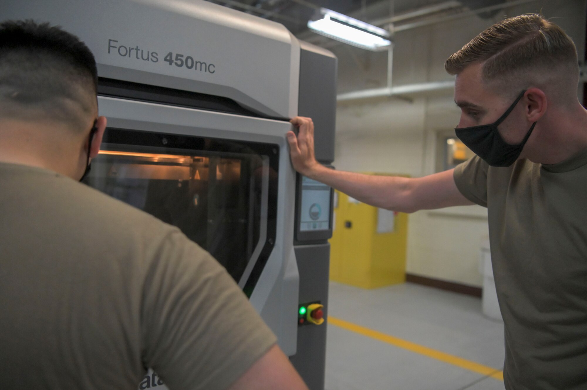 Airmen monitor 3-D printer beginning to power on.