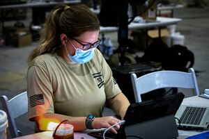 210826-A-YD123-0266 U.S. 5TH FLEET AREA OF OPERATIONS (Aug. 26, 2021) – A U.S. service member processes information on a laptop while assisting U.S. citizens and evacuees arriving from Afghanistan at a location in the U.S. 5th Fleet area of operations prior to onward travel to the United States. The U.S. 5th Fleet region encompasses nearly 2.5 million square miles of water area and is comprised of 20 countries.