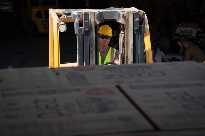 210826-N-ZA692-0017 U.S. 5TH FLEET AREA OF OPERATIONS (Aug. 26, 2021) – A U.S. service member transports supplies in support of U.S. citizens and evacuees arriving from Afghanistan at a location in the U.S. 5th Fleet area of operations prior to onward travel to the United States. The U.S. 5th Fleet region encompasses nearly 2.5 million square miles of water area and is comprised of 20 countries.