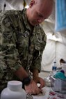 210826-N-ZA692-0765 U.S. 5TH FLEET AREA OF OPERATIONS (Aug. 26, 2021) – A U.S. service member processes medical supplies while assisting U.S. citizens and evacuees arriving from Afghanistan at a location in the U.S. 5th Fleet area of operations prior to onward travel to the United States. The U.S. 5th Fleet region encompasses nearly 2.5 million square miles of water area and is comprised of 20 countries. (U.S. Navy photo by Mass Communication Specialist 2nd Class Anita Chebahtah)