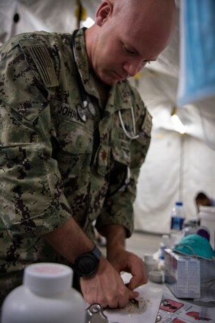 210826-N-ZA692-0765 U.S. 5TH FLEET AREA OF OPERATIONS (Aug. 26, 2021) – A U.S. service member processes medical supplies while assisting U.S. citizens and evacuees arriving from Afghanistan at a location in the U.S. 5th Fleet area of operations prior to onward travel to the United States. The U.S. 5th Fleet region encompasses nearly 2.5 million square miles of water area and is comprised of 20 countries. (U.S. Navy photo by Mass Communication Specialist 2nd Class Anita Chebahtah)