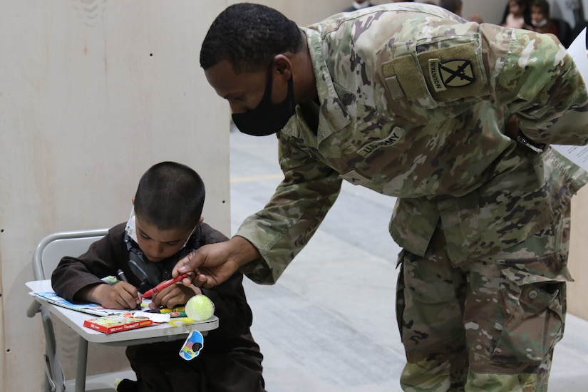 A U.S. Army Soldier and Afghan evacuee boy color together at Camp Buehring, Kuwait, Aug. 25, 2021. Soldiers joined in activities with the children as their families went through arrival processes at the facility. (U.S. Army photo by Sgt. Marc Loi)