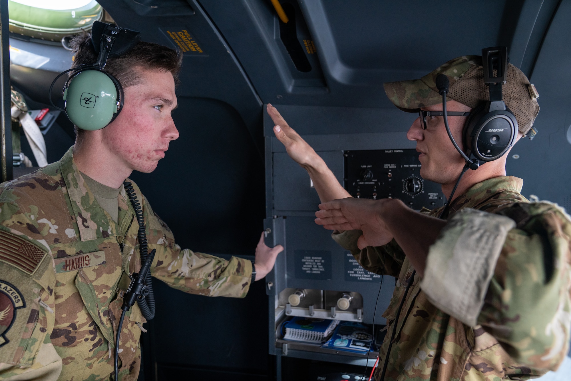 U.S. Air Force Airman 1st Class Andrew Harris, a 39th Airlift Squadron C-130J Super Hercules loadmaster from Dyess Air Force Base, Texas, and Staff Sgt. Nolan Brandt, a 39th Airlift Squadron C-130J Super Hercules instructor loadmaster from Dyess AFB, Texas, discuss flight maneuvers during a RED FLAG-Alaska 21-3 sortie.