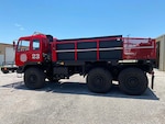 A former military truck is show with a new red paint job and now looking like a fire truck.