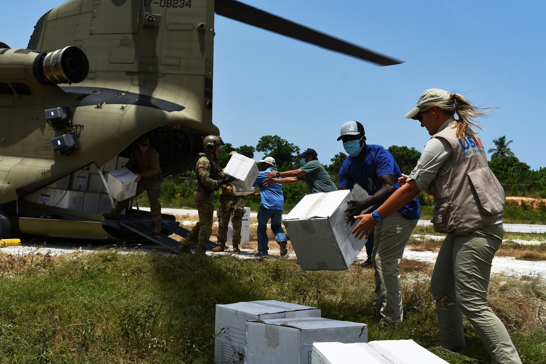 U.S. service members work with civilians to unpack relief supplies from a helicopter.