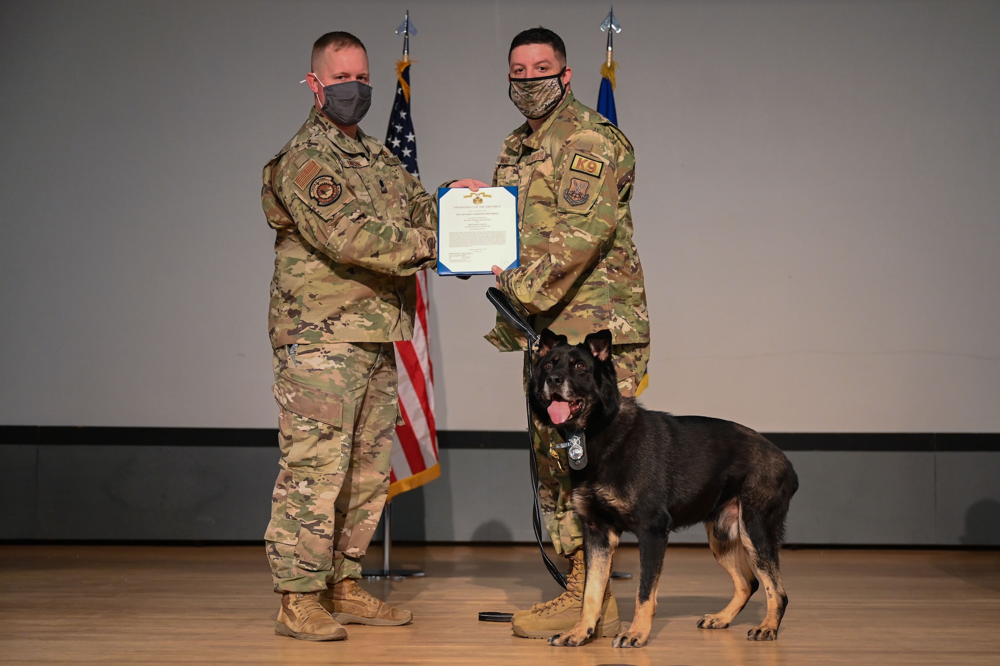 U.S. Air Force Staff Sgt. Matthew Mead, 377th Security Forces Squadron Military Working Dog handler, accepts a commendation for MWD Baxi from Lt. Col. Adam Morgan, 377th SFS commander, during a retirement ceremony at Kirtland Air Force Base, N.M., Aug. 27, 2021.
