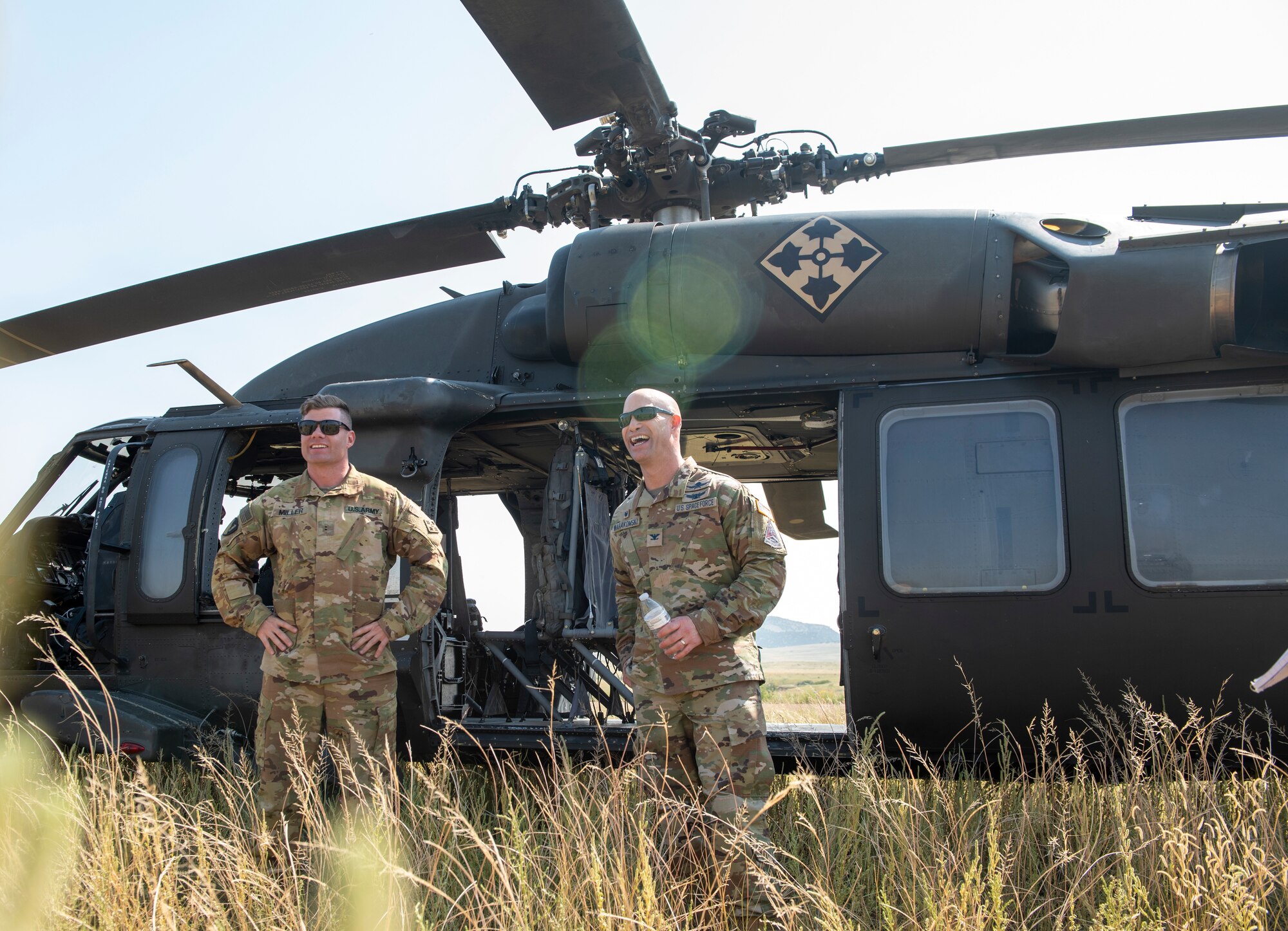 U.S. Space Force Col. Shay Warakomski, Peterson-Schriever Garrison commander, and U.S. Army Chief Warrant Officer 2 Brandon Miller assigned to 2-4 General Support Aviation Battalion, 4th Combat Aviation Brigade, 4th Infantry Division enjoy a moment after landing at Fort Carson, Colorado. Warakomski visited Airmen and Guardians participating in the chemical, biological, radiological and nuclear defense exercise that took place at Camp Red Devil on Fort Carson, which is a simulated deployment area.  (U.S. Space Force photo by Airman 1st Class Kaitlin Castillo)