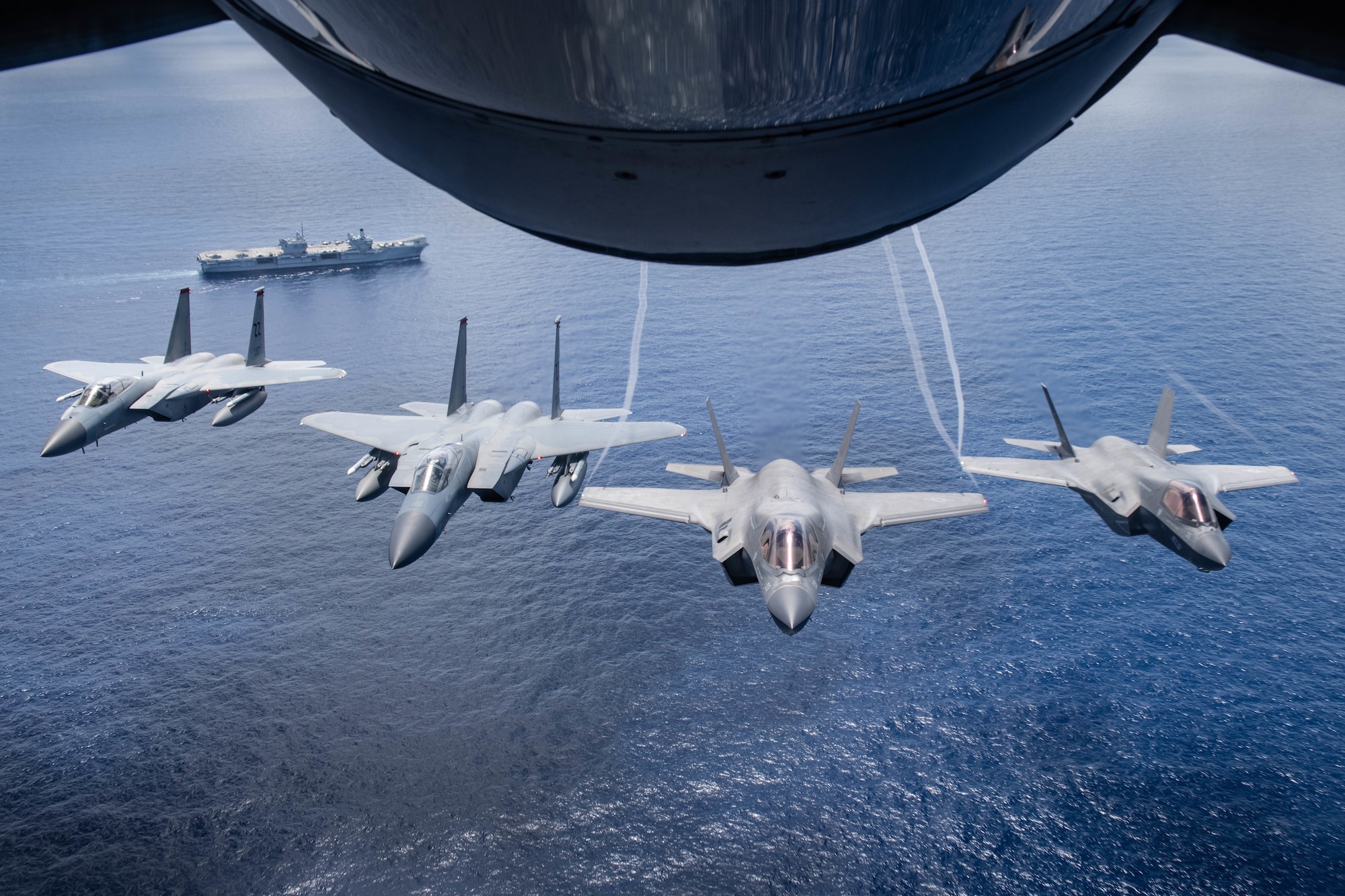 Two U.S. Marine Attack Squadron 211 F-35B Lightning IIs, assigned to the United Kingdom Carrier Strike Group, and two U.S. Air Force F-15 Eagles, assigned to the 67th Fighter Squadron, Kadena Air Base, Japan fly over U.K. aircraft carrier HMS Queen Elizabeth, during a Large Scale Global Exercise 21 mission over the western Pacific Ocean, Aug. 24, 2021. Kadena Air Base participated in LSGE 21, which allows the U.S. to train with allies and partners to improve shared understanding, trust, and interoperability on security challenges impacting all nations. (U.S. Air Force photo by Staff Sgt. Kyle Johnson)