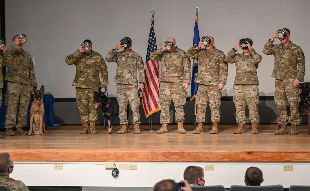 A group of Airmen from the 377th Security Forces Squadron toast Military Working Dog’s Baxi and Ggarbo during their retirement ceremony at Kirtland Air Force Base.