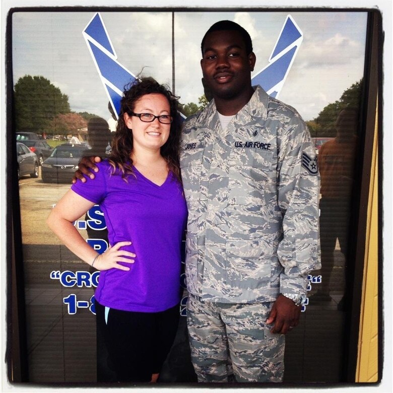 Woman and man stand and smile in front of a window.