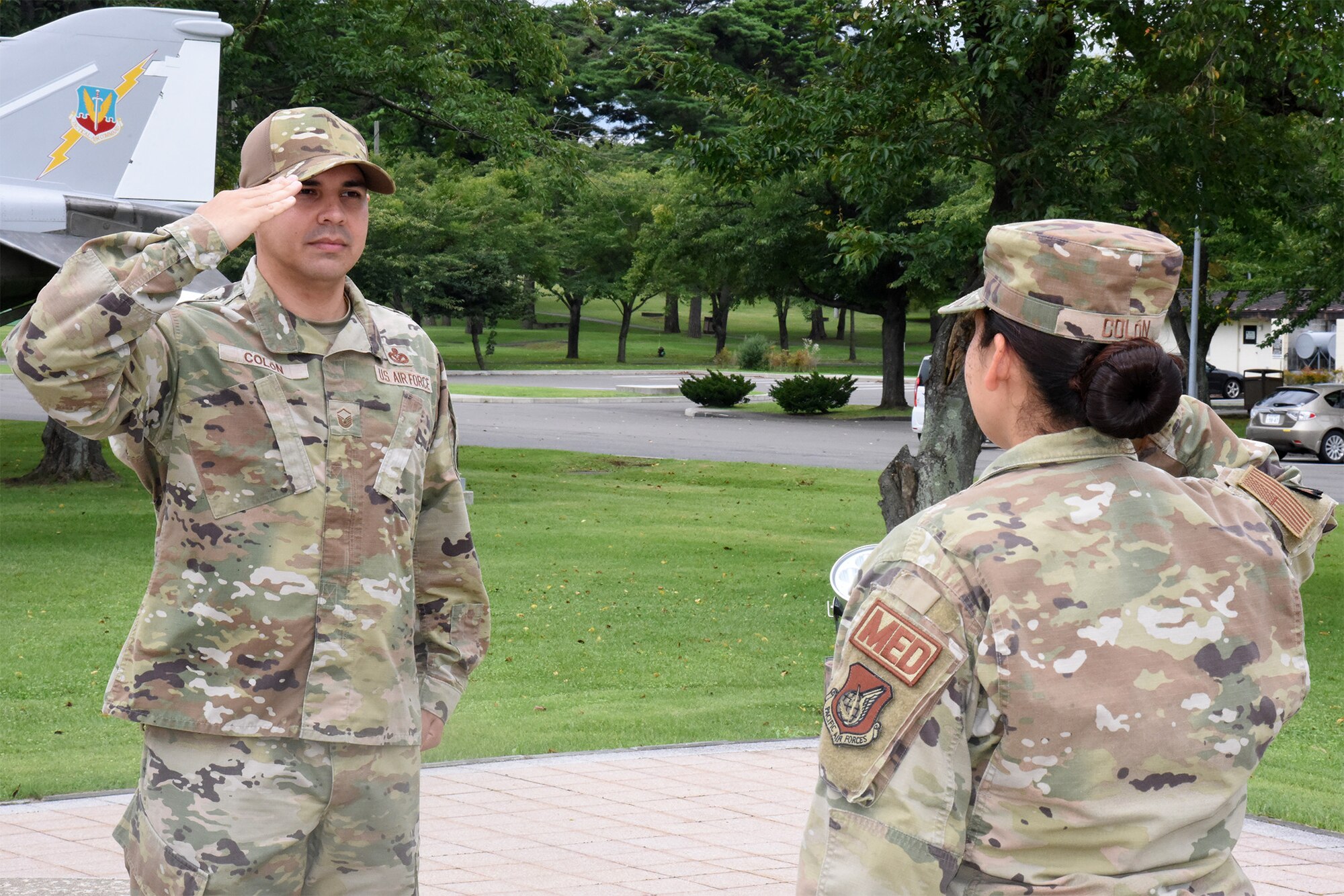 A man in a military uniform salutes a woman in a military uniform during a re-enlistment ceremony.