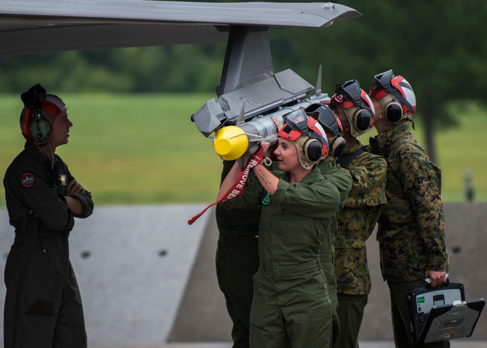 Five Marines hoist a missile to be uploaded to an F-35 fighter jet.