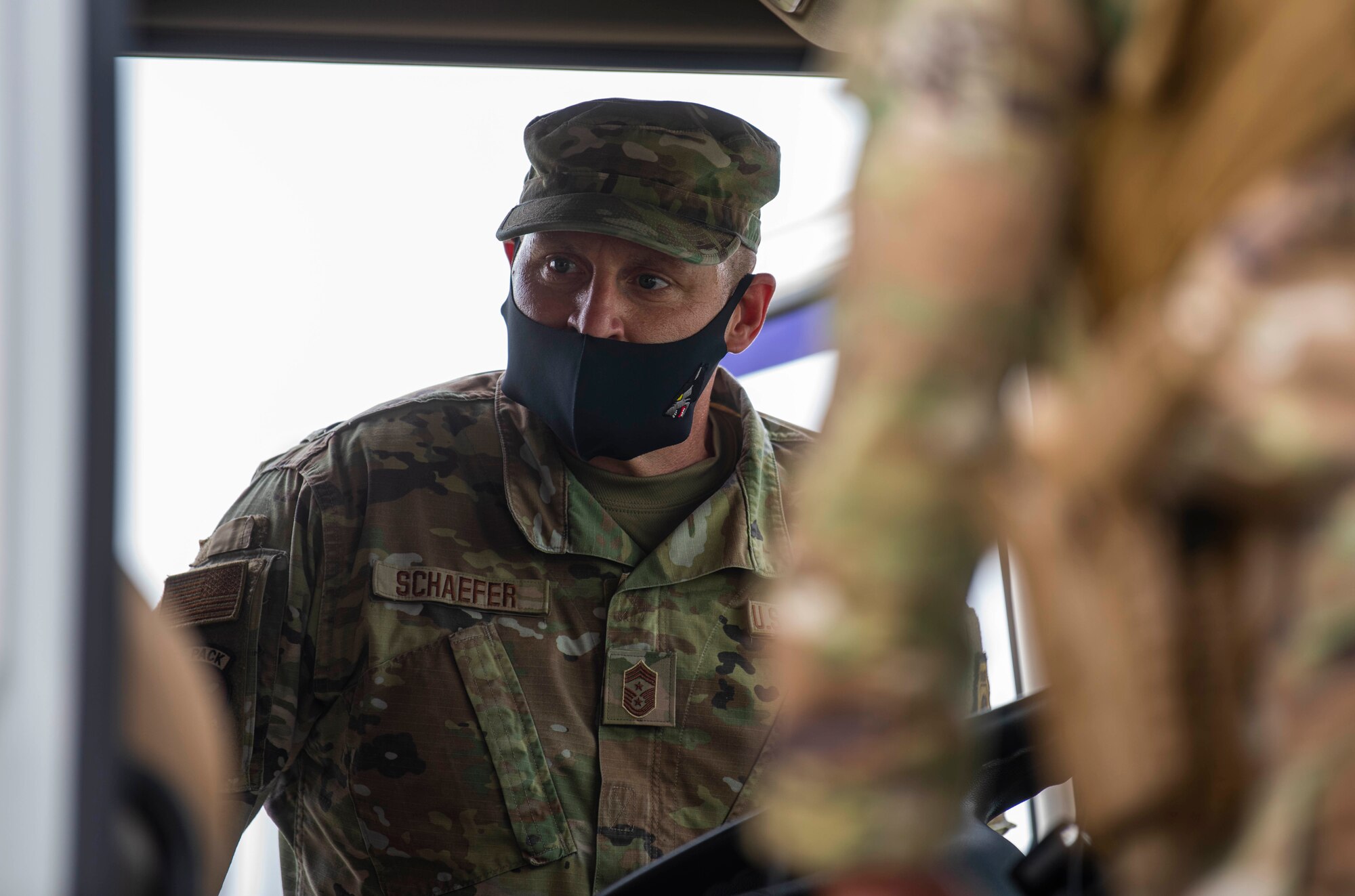 A chief watches Airmen inspect vehicles.