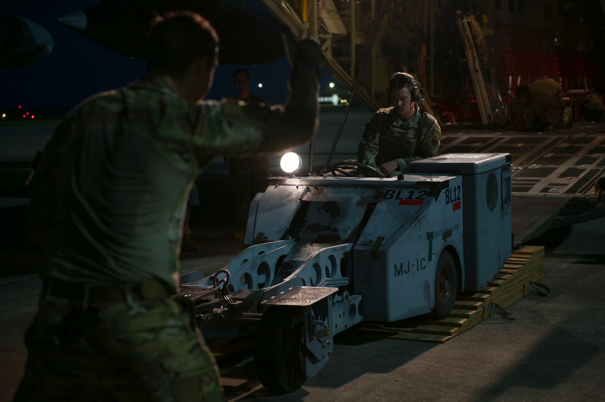 A photo of an Airman reversing an MJ-1C lift truck into the back of an HC-130J Combat King II.