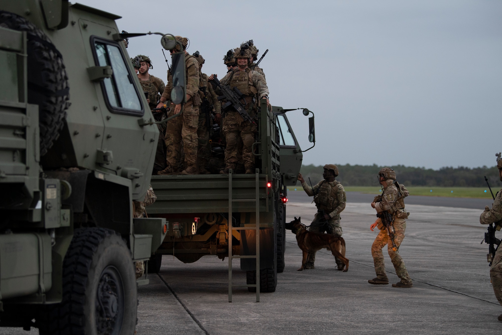 A photo of multiple Airmen standing in the back of a light medium tactical vehicle and three airman standing on the ground next to it.