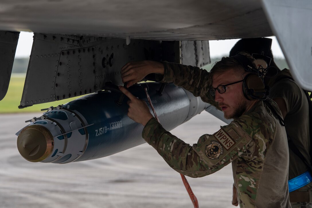 A photo of an Airman touching a GDU-38 bomb on the underside of an A-10C Thunderbolt II.