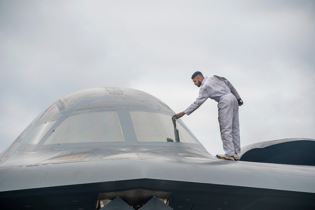 An airman stands on an aircraft while making fixes.