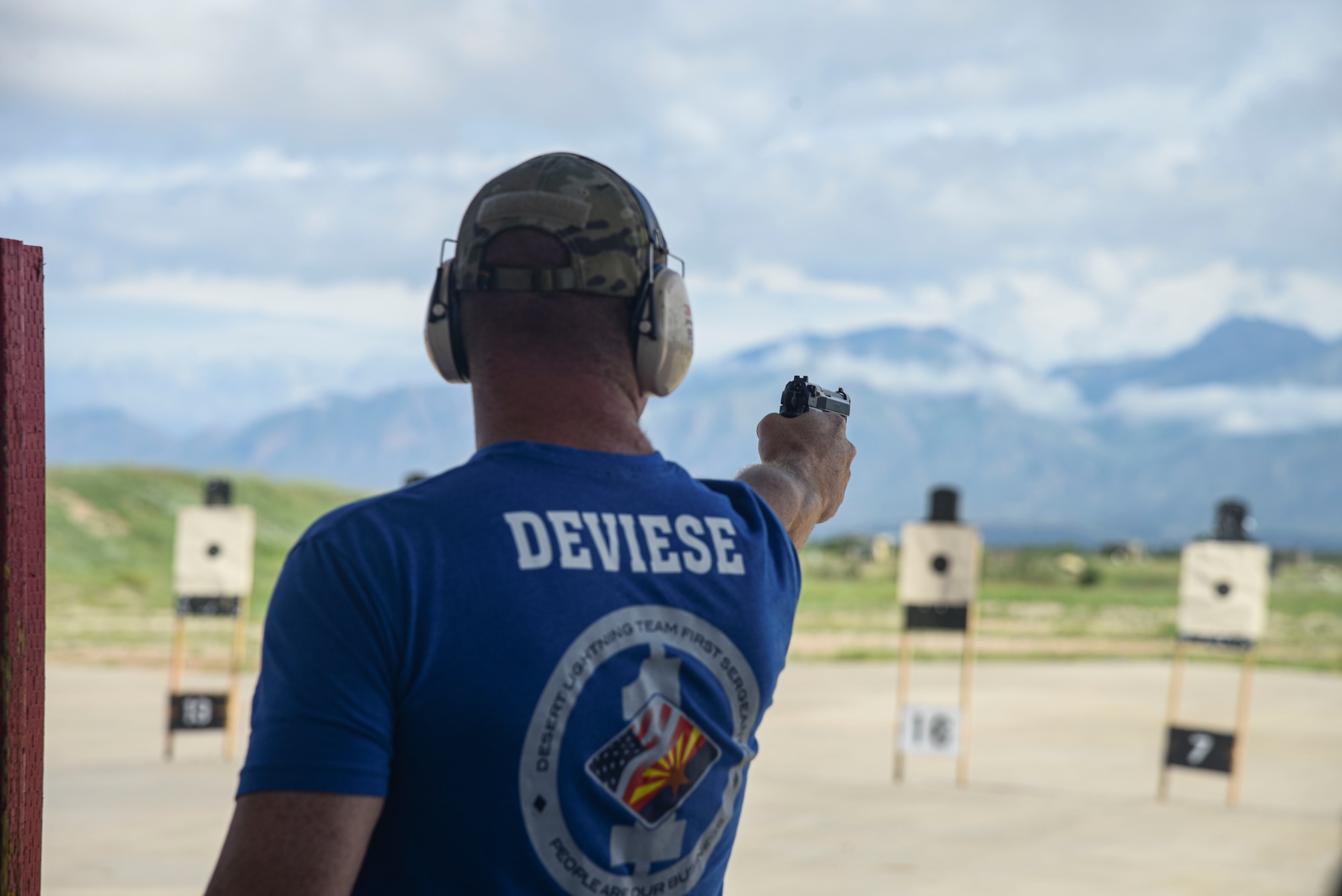 A photo of an Airman firing a pistol at a target.