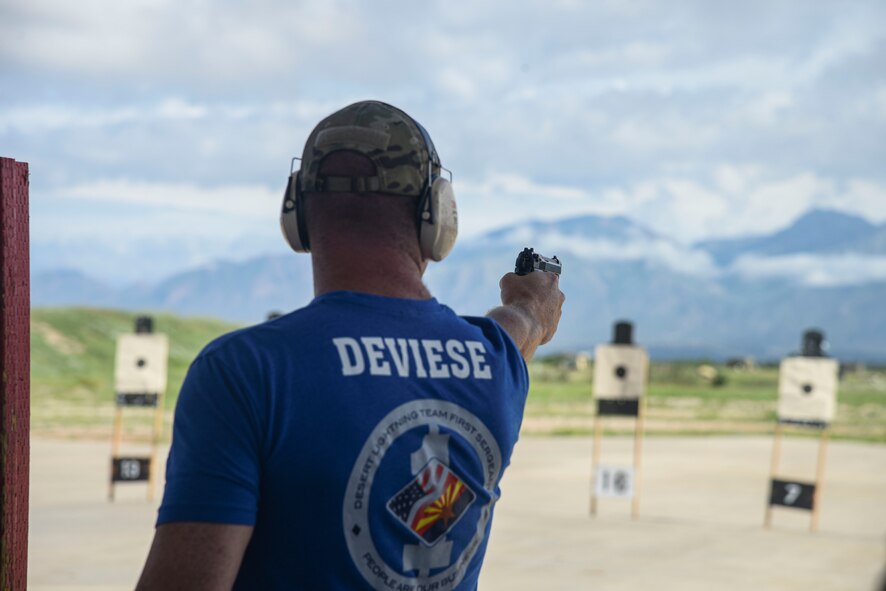 A photo of an Airman firing a pistol at a target.