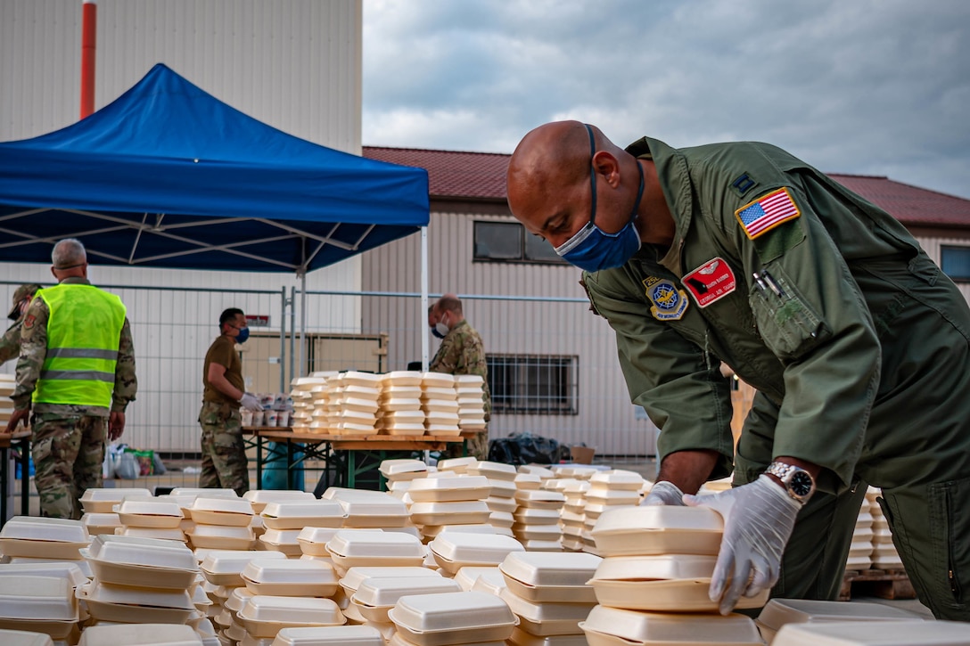 An airman stacks food containers outside.