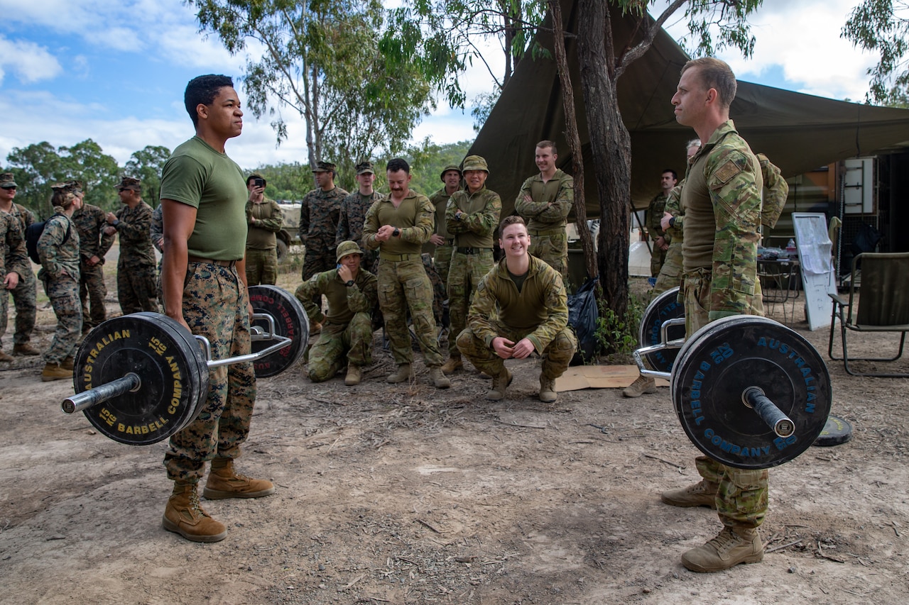 Two service members hold weights.
