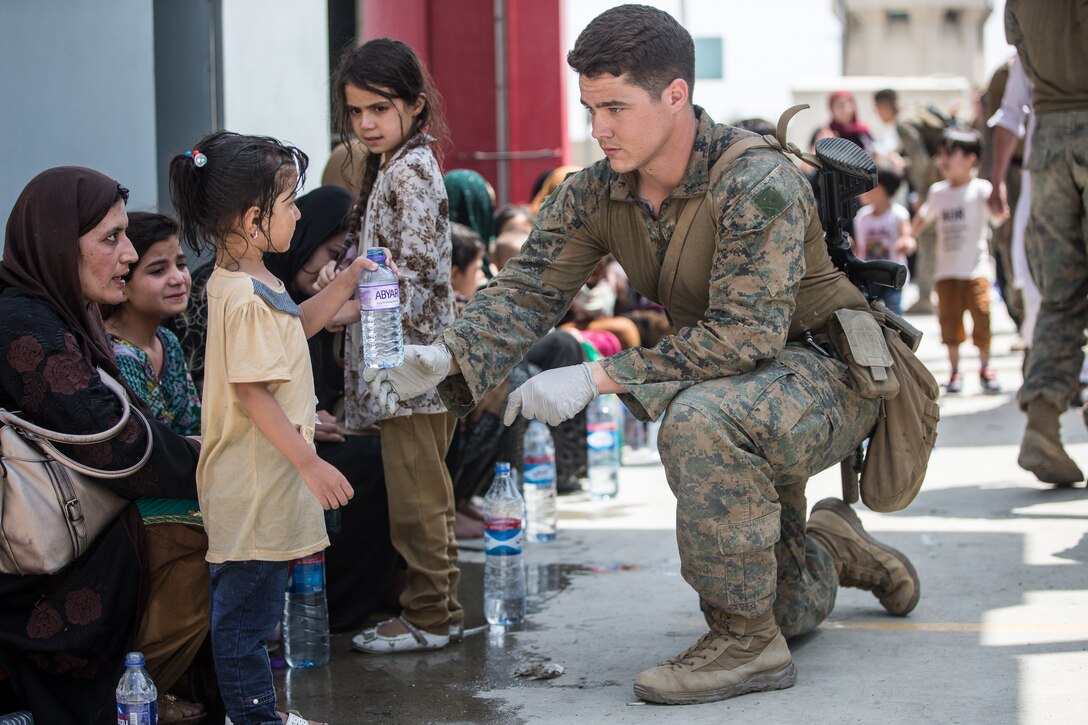 A Marine with the 24th Marine Expeditionary Unit (MEU) provides fresh water to a child during an evacuation at Hamid Karzai International Airport, Kabul, Afghanistan, Aug. 20. U.S. service members are assisting the Department of State with an orderly drawdown of designated personnel in Afghanistan. (U.S. Marine Corps photo by Sgt. Samuel Ruiz).