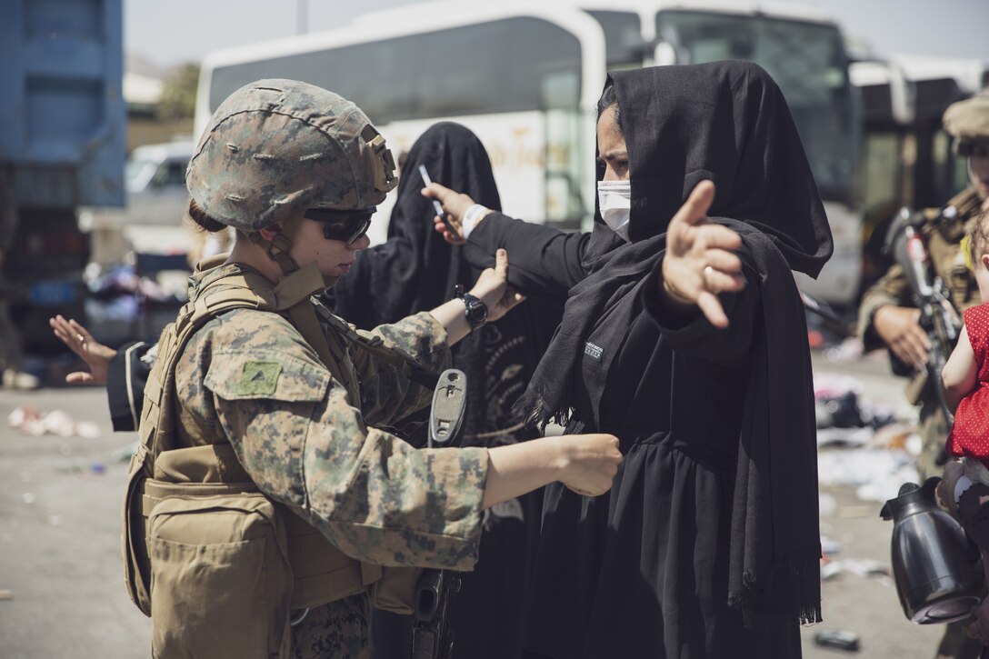 210828-M-AU949-0273 HAMID KARZAI INTERNATIONAL AIRPORT, Afghanistan (August 28, 2021) A U.S. Marine with the 24th Marine Expeditionary Unit (MEU) checks an Afghan woman as she goes through the Evacuation Control Center (ECC) during an evacuation at Hamid Karzai International Airport, Kabul, Afghanistan, Aug. 28. U.S. service members are assisting the Department of State with a non-combatant evacuation operation (NEO) in Afghanistan. (U.S. Marine Corps photo by Staff Sgt. Victor Mancilla)