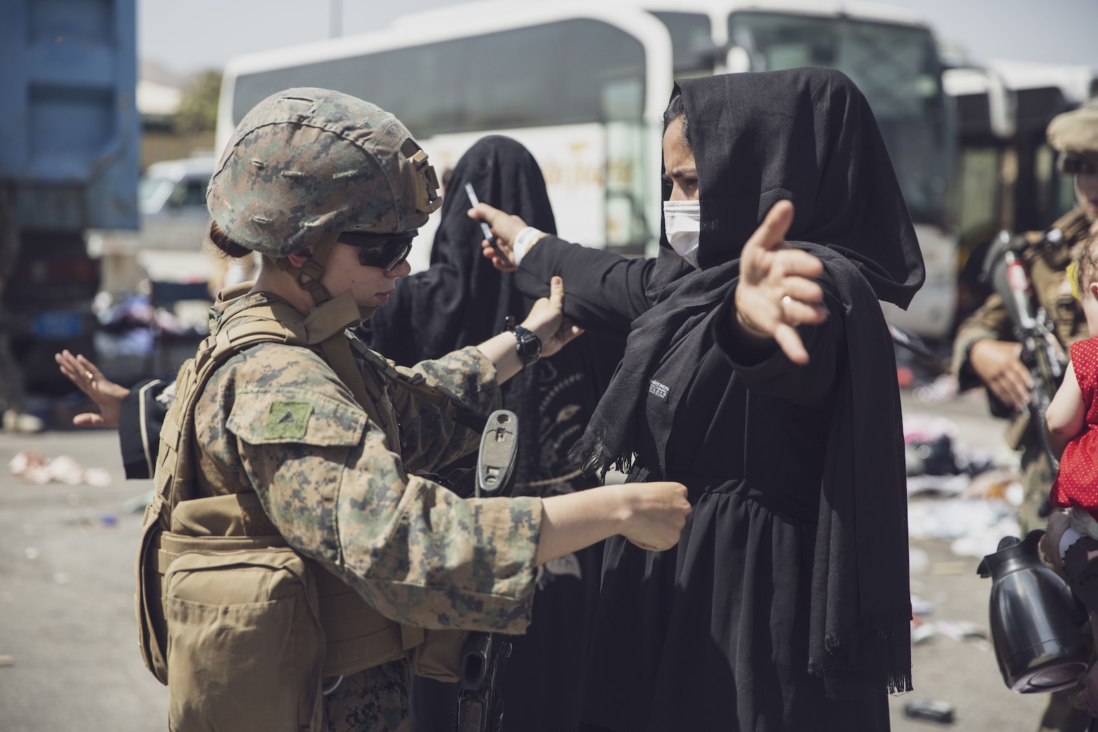 A U.S. Marine with the 24th Marine Expeditionary Unit (MEU) checks an Afghan woman as she goes through the Evacuation Control Center (ECC) during an evacuation at Hamid Karzai International Airport, Kabul, Afghanistan, Aug. 28. U.S. service members are assisting the Department of State with a non-combatant evacuation operation (NEO) in Afghanistan. (U.S. Marine Corps photo by Staff Sgt. Victor Mancilla)