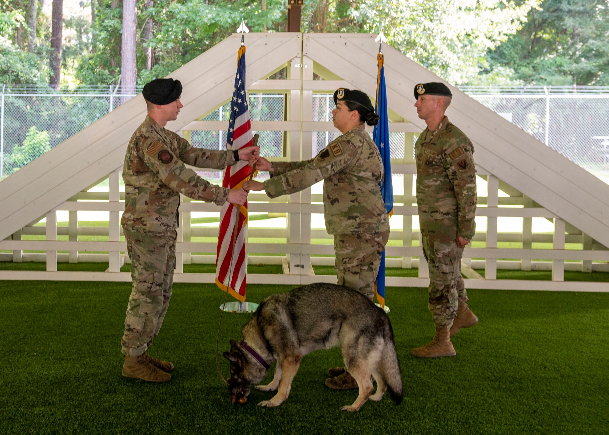 Capt. Samuel Doyel, left, 4th Security Forces Squadron operations officer, passes military working dog Gina’s leash to Staff Sgt. Maegan-Ann Baptista, middle, 4th Security Forces Squadron MWD hander, to symbolize ownership during Gina’s retirement ceremony at Seymour Johnson Air Force Base, North Carolina, Aug. 26, 2021.