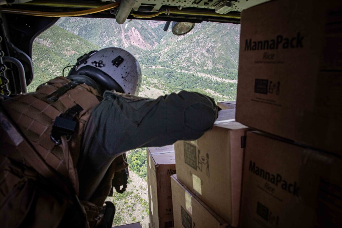 Naval Aircrewman (Helicopter) 1st Class Robert McCann looks out of an MH-60S Sea Hawk helicopter as it prepares to deliver food in Cavaillon, Haiti as part of a humanitarian aid mission, Aug. 28.