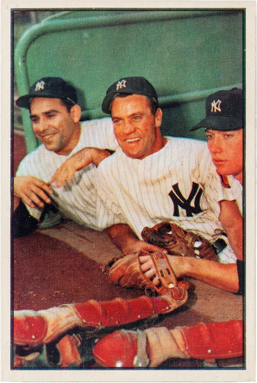 Three baseball players pose for a photo in the dugout.