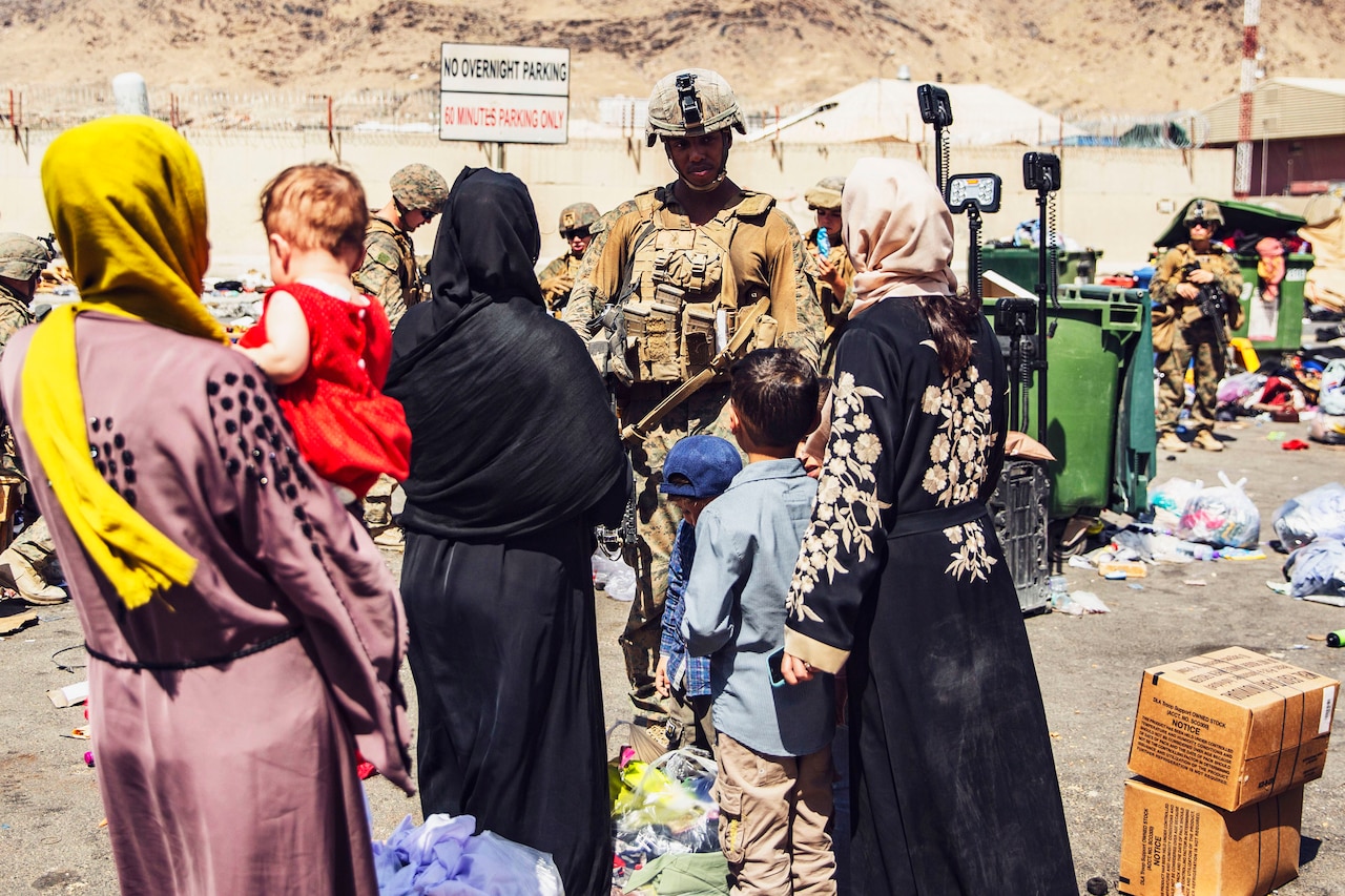 A Marine talks to civilians outdoors.