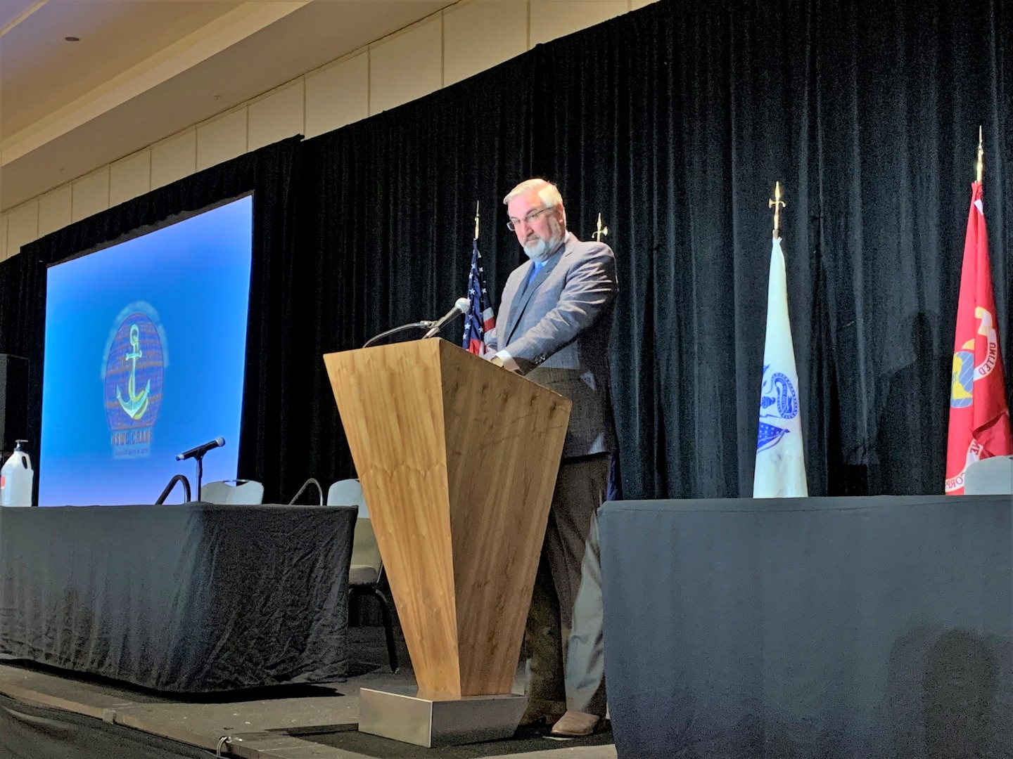 A man stands at a podium on stage and speaks.