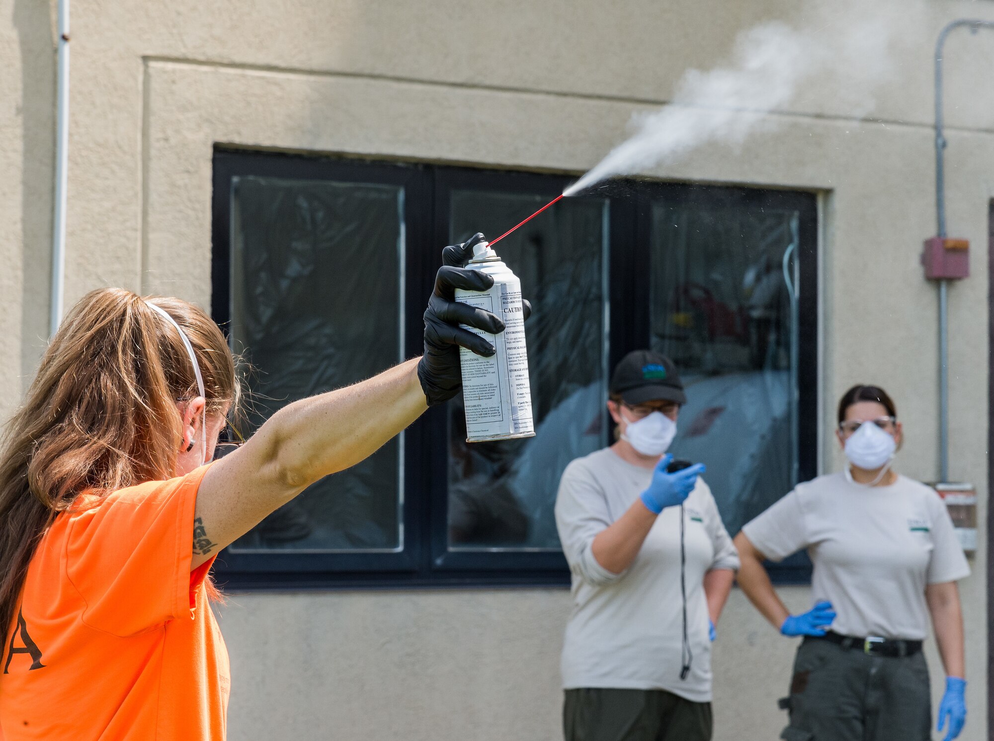 Emily Wallis, U.S. Department of Agriculture biological science laboratory technician, releases a six-second application of 10% d-Phenothrin insecticide at Dover Air Force Base, Delaware, Aug. 19, 2021. Melissa Benzinger McGlynn, USDA biological science laboratory technician, timed the release, as Lianmarie Colon Torres, USDA plant health safeguard specialist, recorded and formulated an optimal application time to use in Spotted Lanternfly experiments. (U.S. Air Force photo by Roland Balik)