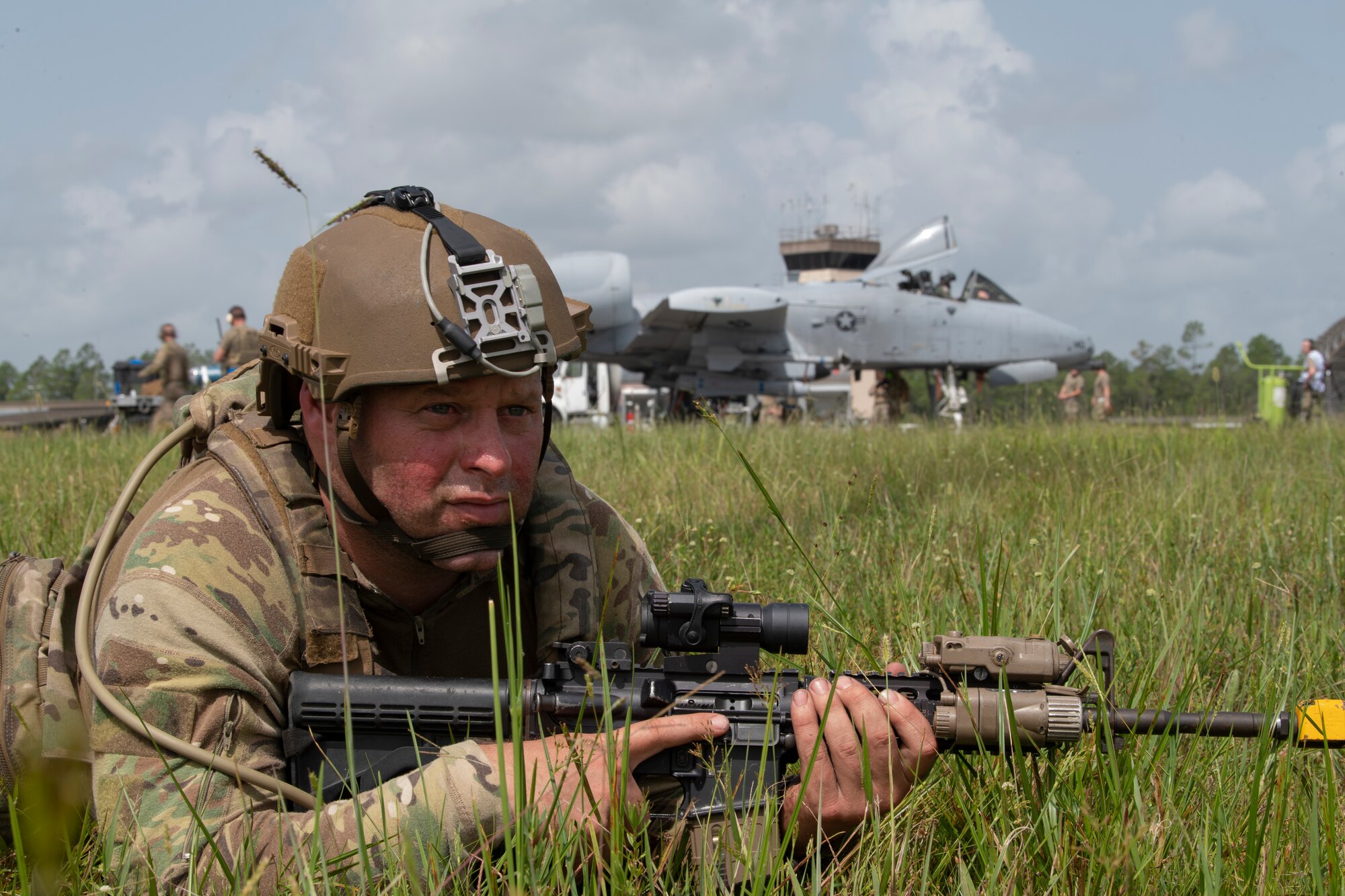 A photo of a man laying on the ground positioned with a weapon for securing the area.