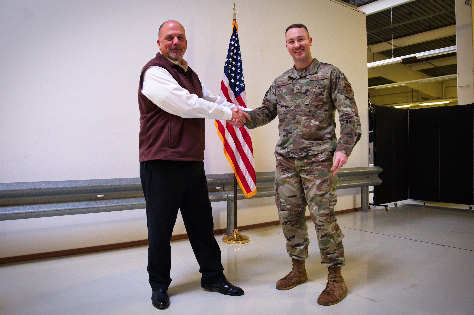 Scott Lockard, 86th Airlift Wing vice director, recognizes U.S. Air Force Staff Sgt. David Smith, 786th Civil Engineer Squadron emergency management craftsman, as Airlifter of the Week at Ramstein Air Base, Germany, Nov. 10, 2021. Smith contributed to OAW where he led 441 members, resulting in 554 tents being deployed, 1.5 million meals served, $168 million in assets utilized and 35 thousand travelers granted safe passage. (U.S. Air Force photo by Senior Airman Branden Rae)
