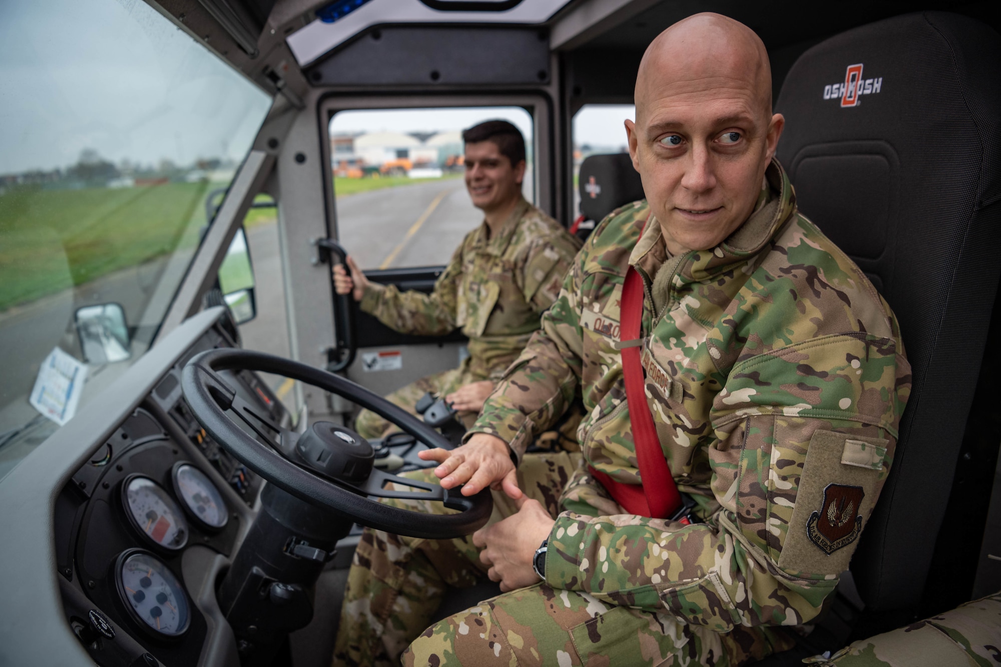 U.S. Air Force Brig. Gen. Josh Olson, right, 86th Airlift Wing commander, drives a firetruck during a 424th Air Base Squadron immersion tour at Chievres Air Base, Belgium, Nov. 16, 2021. Senior Airman Trenton Meuller, left, 424 ABS driver operator, explained to Olson how to operate the vehicle. During the 424 ABS immersion tour, Chievres provided the 86 AW commander with an up-close look at the day to day operations there. It is the mission of fire protection Airmen to ensure the safety of others and to assist civilian fire departments when needed.   (U.S. Air Force photo by Airman Jared Lovett)