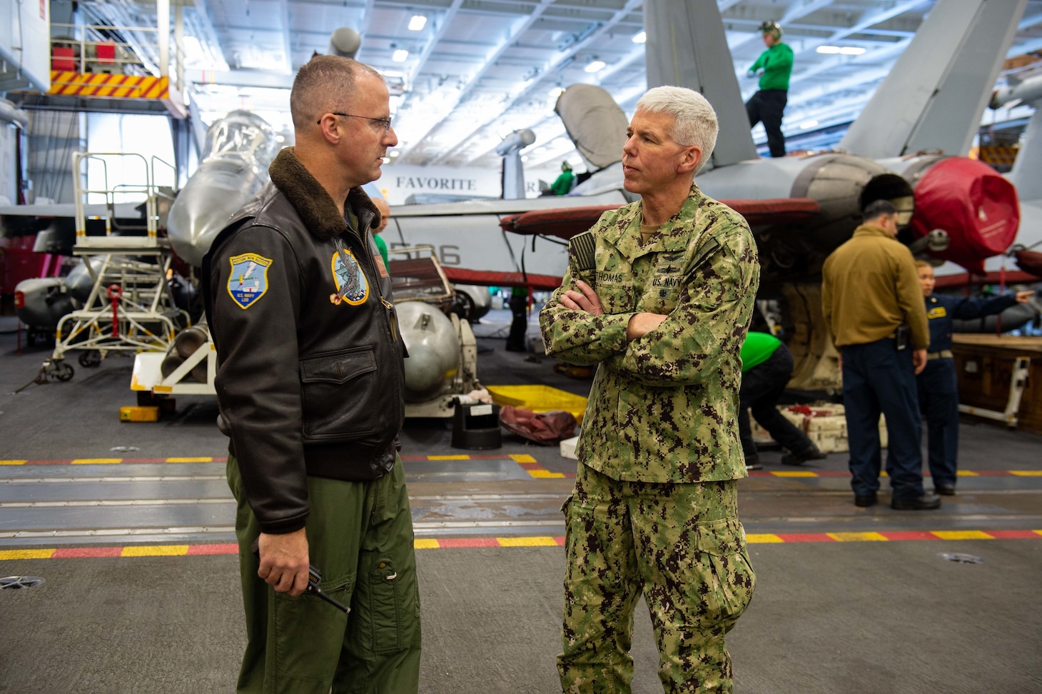 211130-N-IW069-1113 PHILIPPINE SEA (Nov. 30, 2021) Vice Adm. Karl Thomas, right, commander, U.S. 7th Fleet, and Capt. P. Scott Miller, commanding officer, USS Carl Vinson (CVN 70), brief each other in current events in the hangar bay aboard Nimitz-class aircraft carrier USS Carl Vinson (CVN 70), during Annual Exercise (ANNUALEX) 2021, Nov. 30, 2021. ANNUALEX 2021 is a multilateral exercise conducted by naval elements of the Royal Australian, Royal Canadian, German, Japan Maritime Self-Defense Force (JMSDF) and U.S. navies to demonstrate naval interoperability and a joint commitment to a free, open and inclusive Indo-Pacific. (U.S. Navy photo by Mass Communication Specialist 3rd Class Isaiah M. Williams)