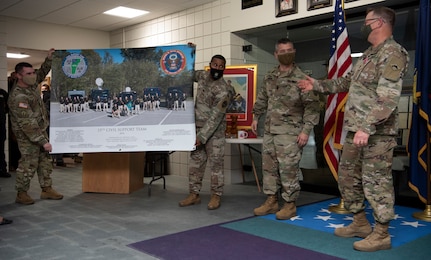 Soldiers with the 15th Civil Support Team present Col. Randall Gates with a poster-sized group photo at his retirement ceremony at Camp Johnson, Vermont, on Nov. 30, 2021. Gates, the Vermont National Guard's director of military support, served as an enlisted Soldier for 11 years and a commissioned officer for 27. (U.S. Army National Guard photo by Don Branum)