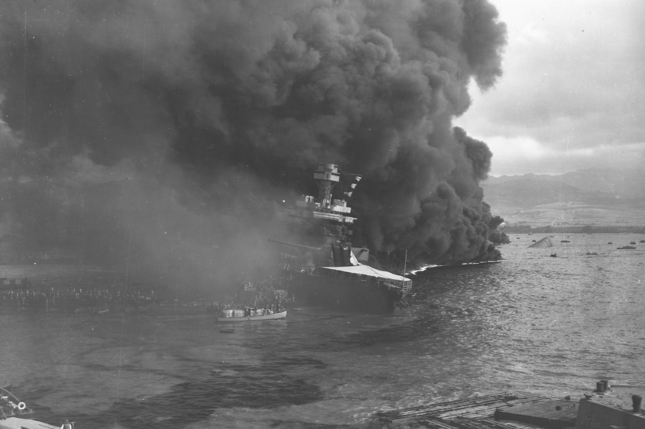 A massive plume of smoke billows from a battleship.